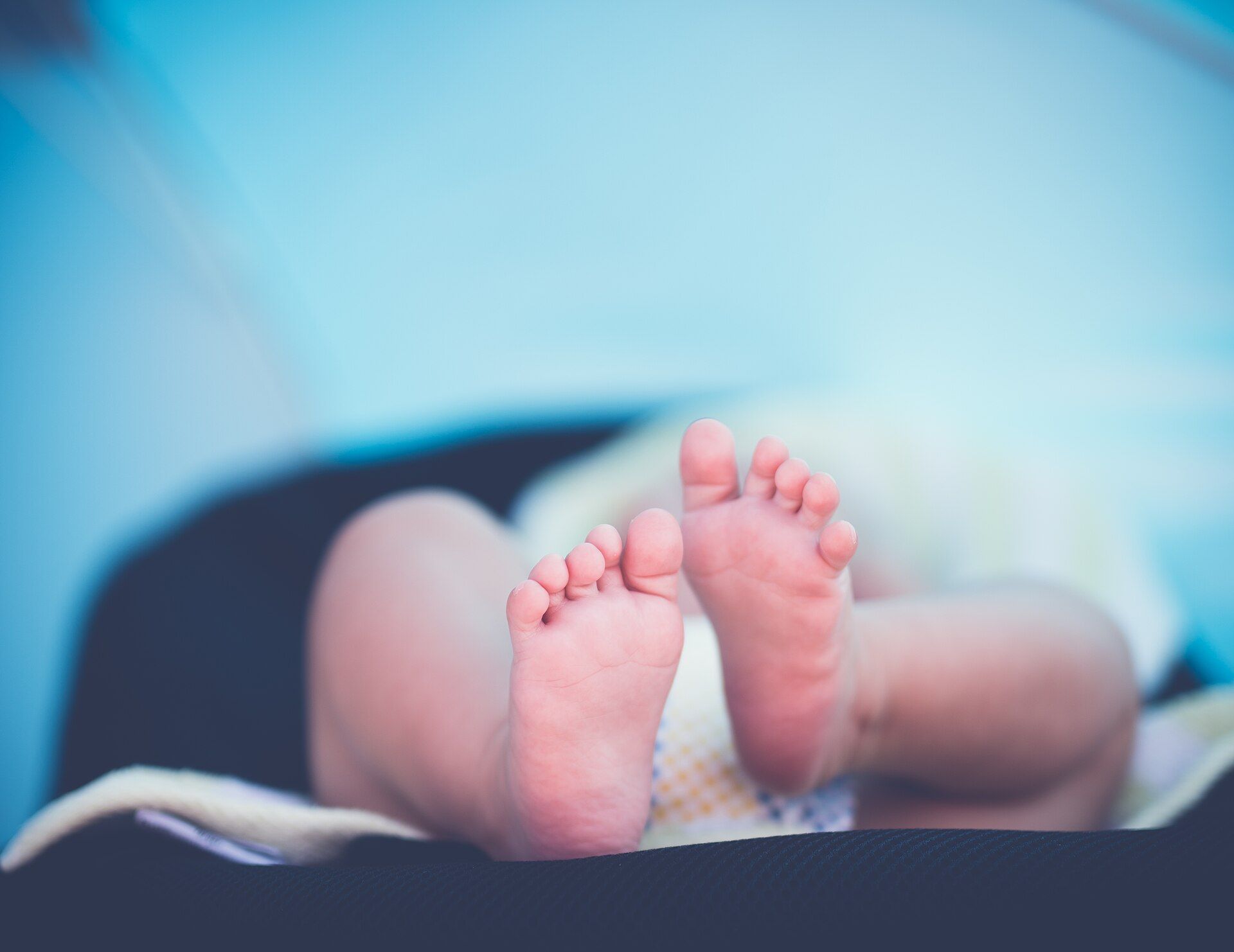 A newborn's feet, lying on a blanket.